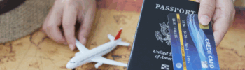 Person hand holding a passport and travel credit card with a toy airplane on a world map
