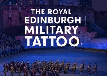 A large group of military performers stands in formation on the Edinburgh Castle esplanade at night, with fireworks lighting the sky. Text overlay reads: "The Royal Edinburgh Military Tattoo – And Why It Happens."
