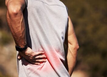 Patient holding lower back in pain, experiencing sciatica symptoms.