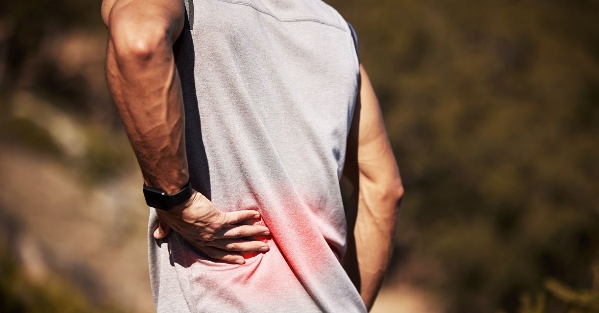 Patient holding lower back in pain, experiencing sciatica symptoms.