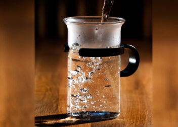 Glass of steaming hot water on a kitchen counter, representing the Ayurvedic practice of Ushnodaka for health and longevity