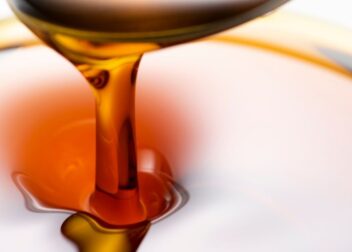 Golden sesame oil in a bowl with sesame seeds – Tila Tailam for hair, skin, and wellness